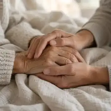 Hands gently holding another person’s hands, representing caregiving and support